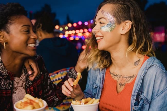 To festivalgjester som spiser mat sammen i skumringen