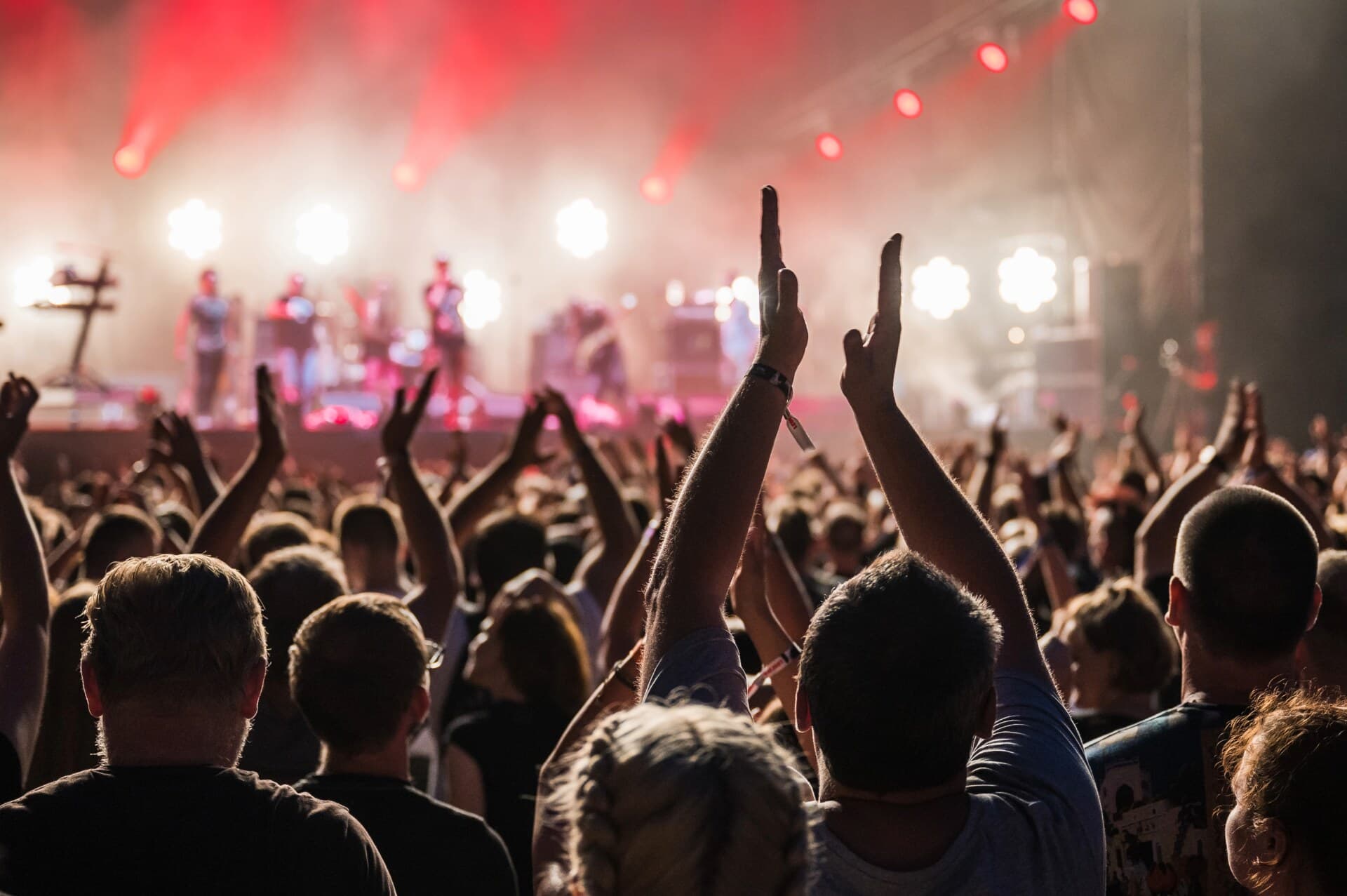 Konsertpublikum med hendene i været foran en opplyst scene
